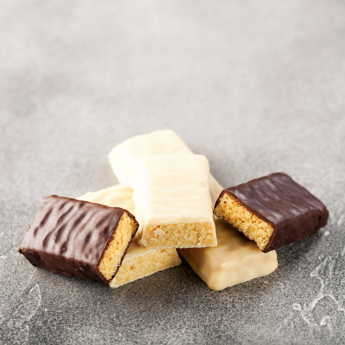 Stack of milk and white chocolate biscuits, cut in half, on a grey background