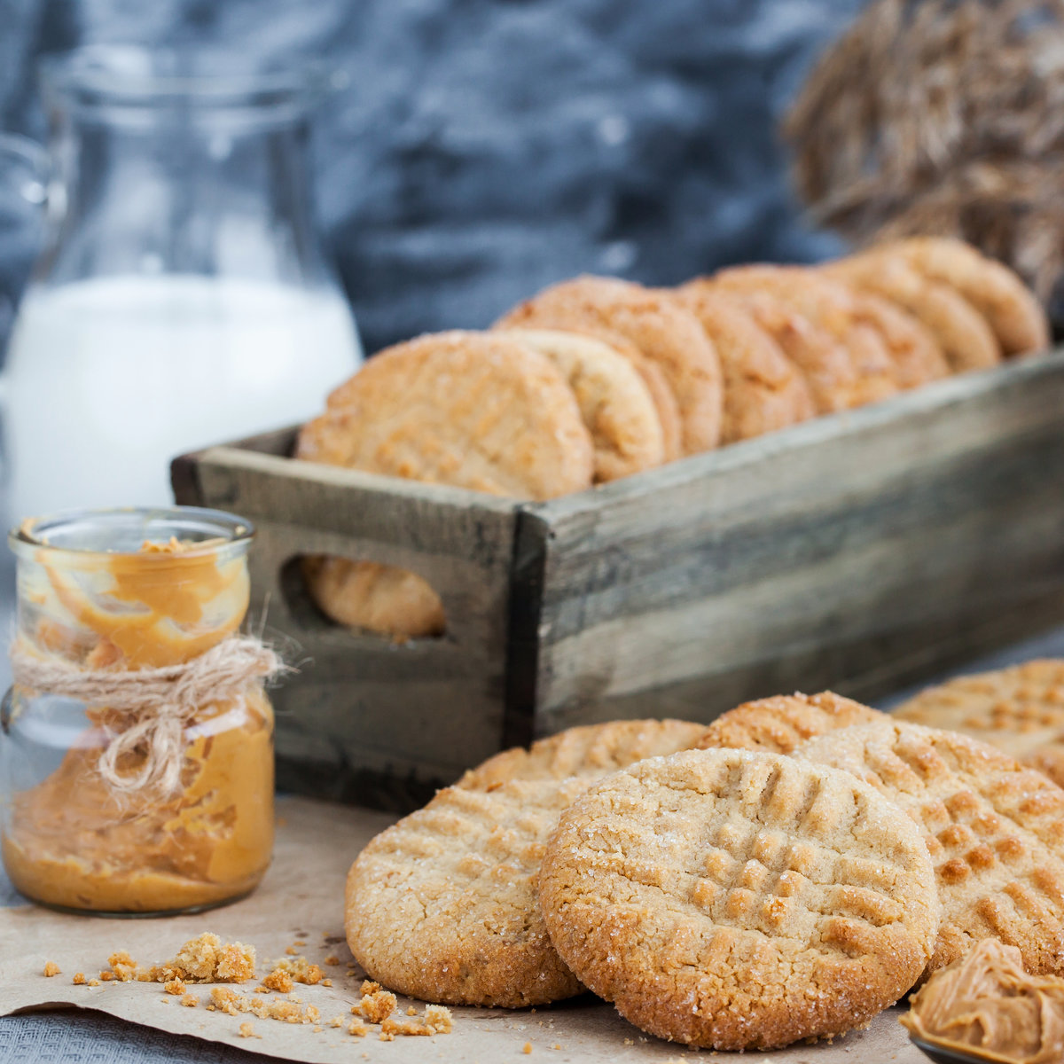 Stack of biscuits on brown paper, in front of a box of biscuits and glass of milk 