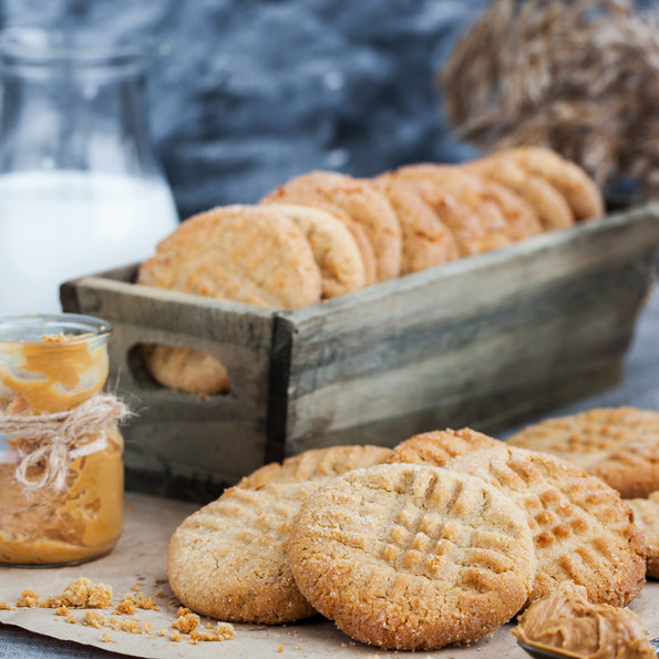 Stack of biscuits on brown paper, in front of a box of biscuits and glass of milk 